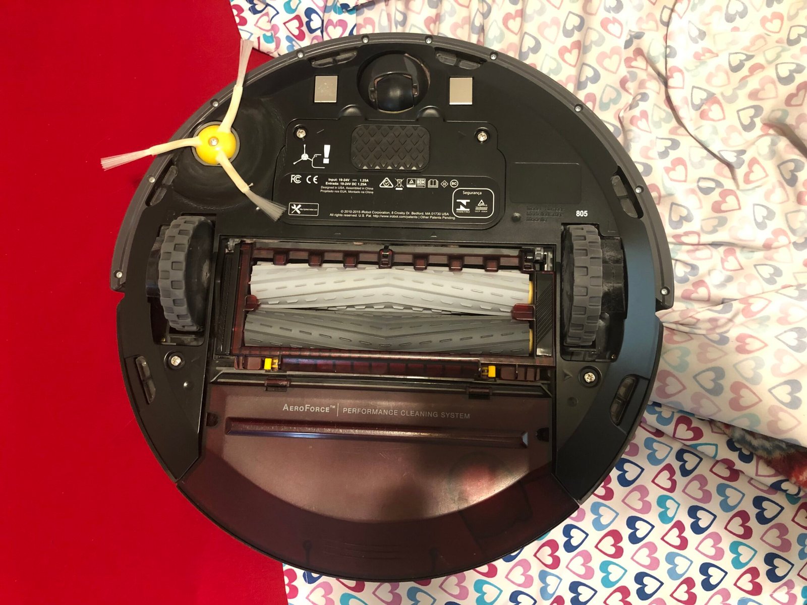 Underside of an iRobot Roomba 805 showing rollers, wheels and side brush
